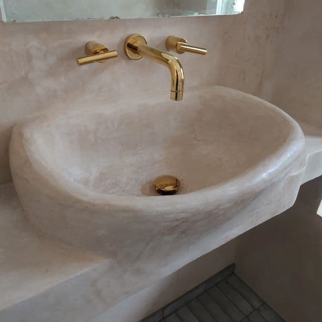 a bathroom sink with two faucets on the side and a mirror above it, classique, tadelakt