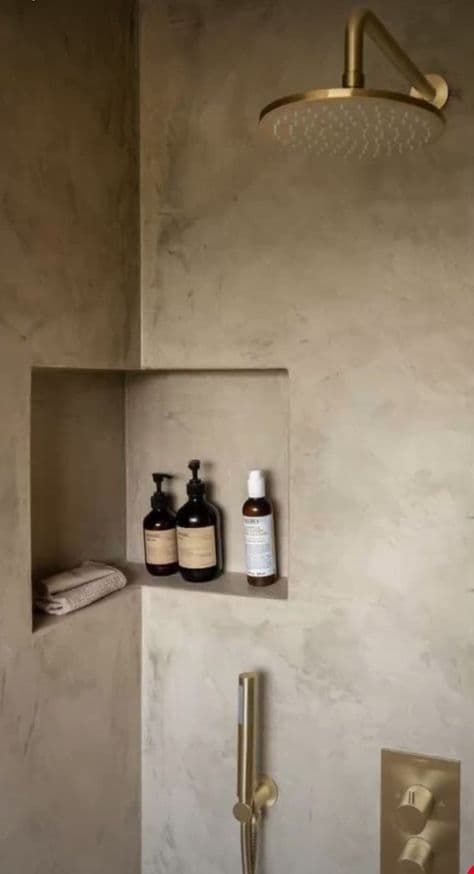 a bathroom with a shower head, soap and lotion bottles on the shelf next to it, classique, tadelakt