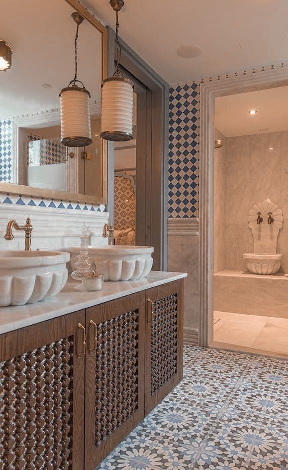 a bathroom with blue and white tiles on the walls, two sinks and a tub, classique, zellige