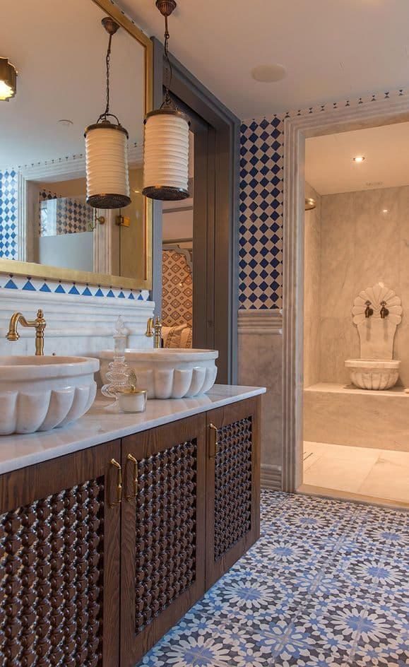 a bathroom with blue and white tiles on the walls, two sinks and a tub, classique, zellige