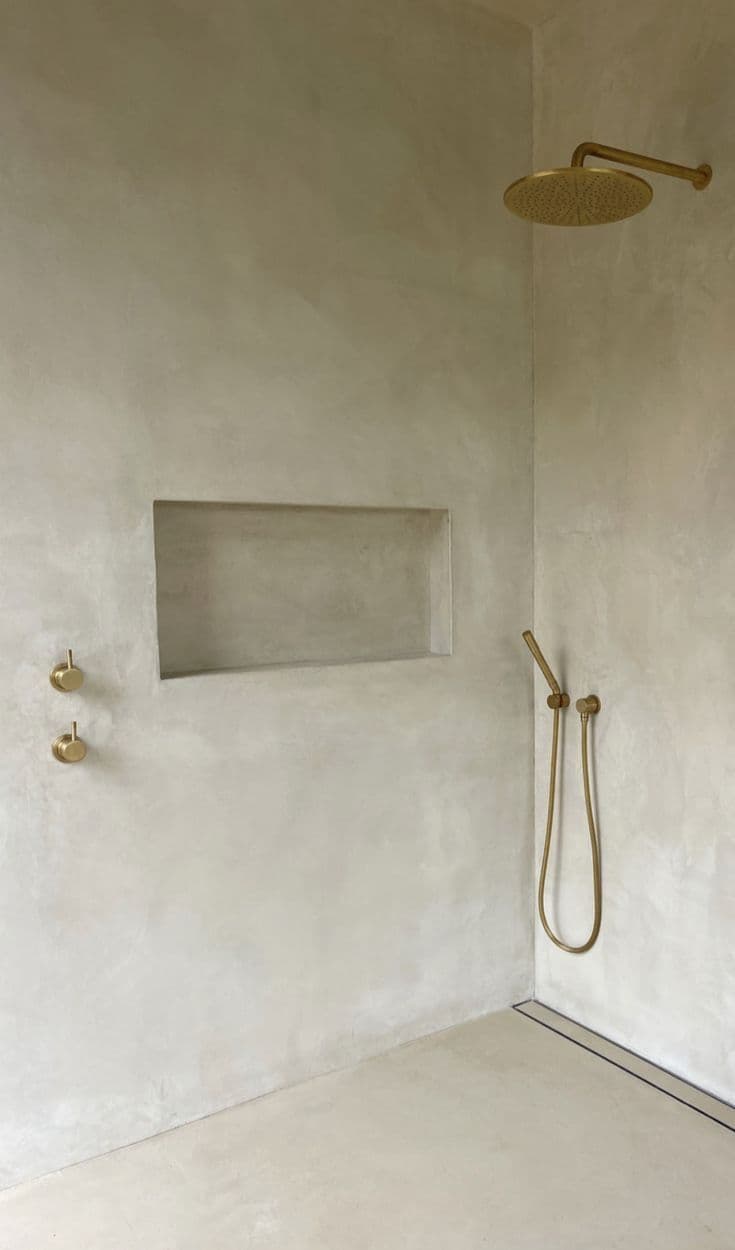 a bathroom with a shower head and hand held shower faucet in the corner, classique, tadelakt