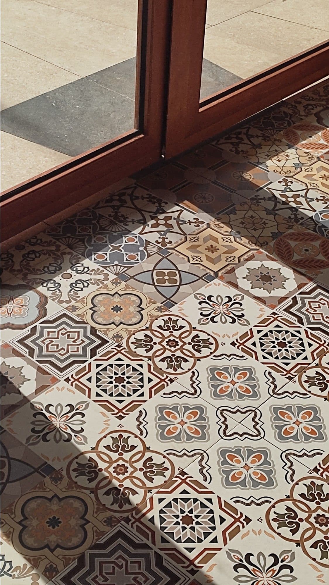a cat is sitting on the floor in front of a glass door and looking outside, classique, tadelakt